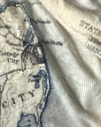 Vintage map with text and topography, partially covered by a textured fabric.