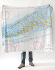 A person standing with a nautical chart blanket draped over their shoulders, displaying detailed map patterns.