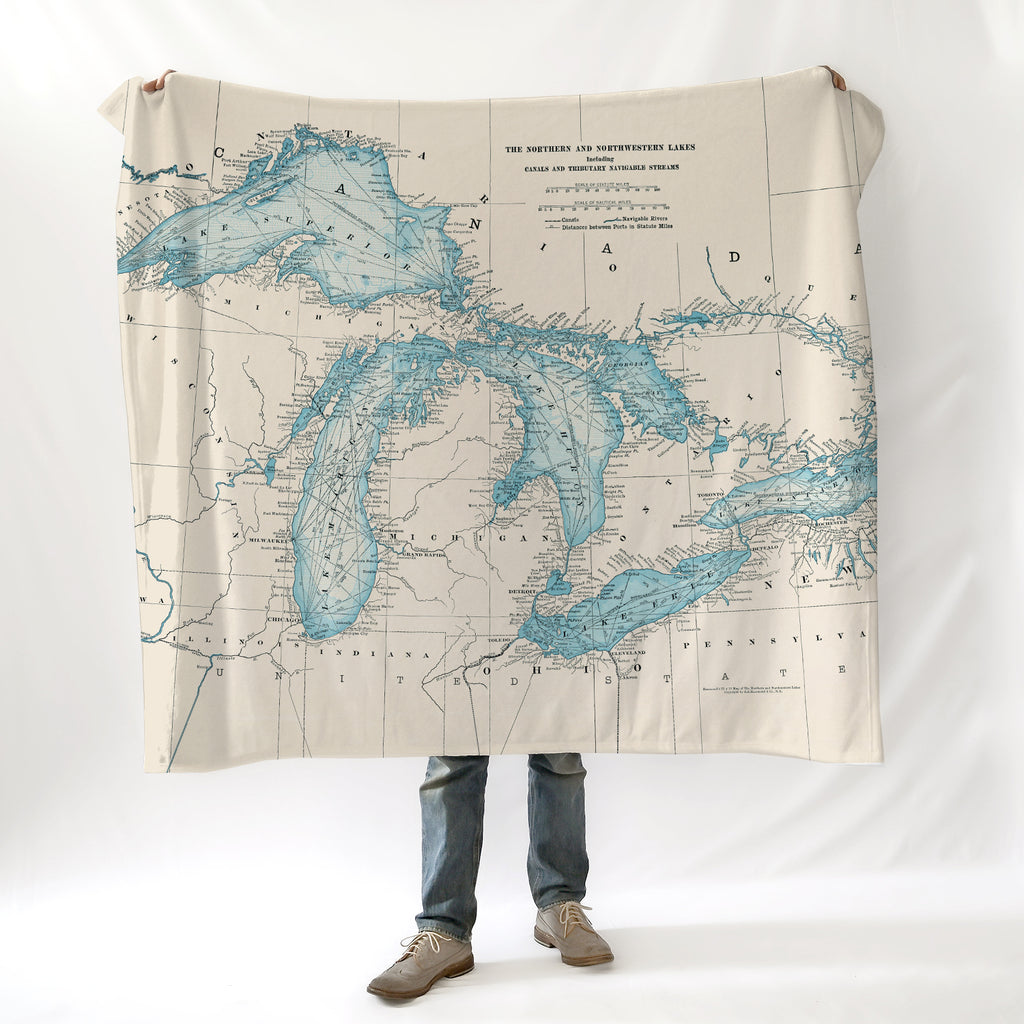 Person holding a blanket with a map design of the Great Lakes on a white background
