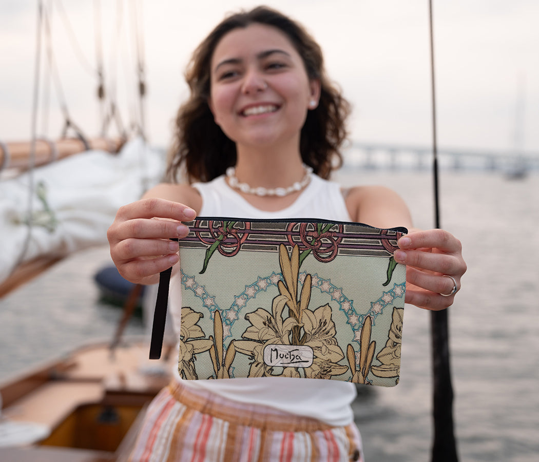 A person holding a wristlet bag with a floral and decorative motif wristlet bag
