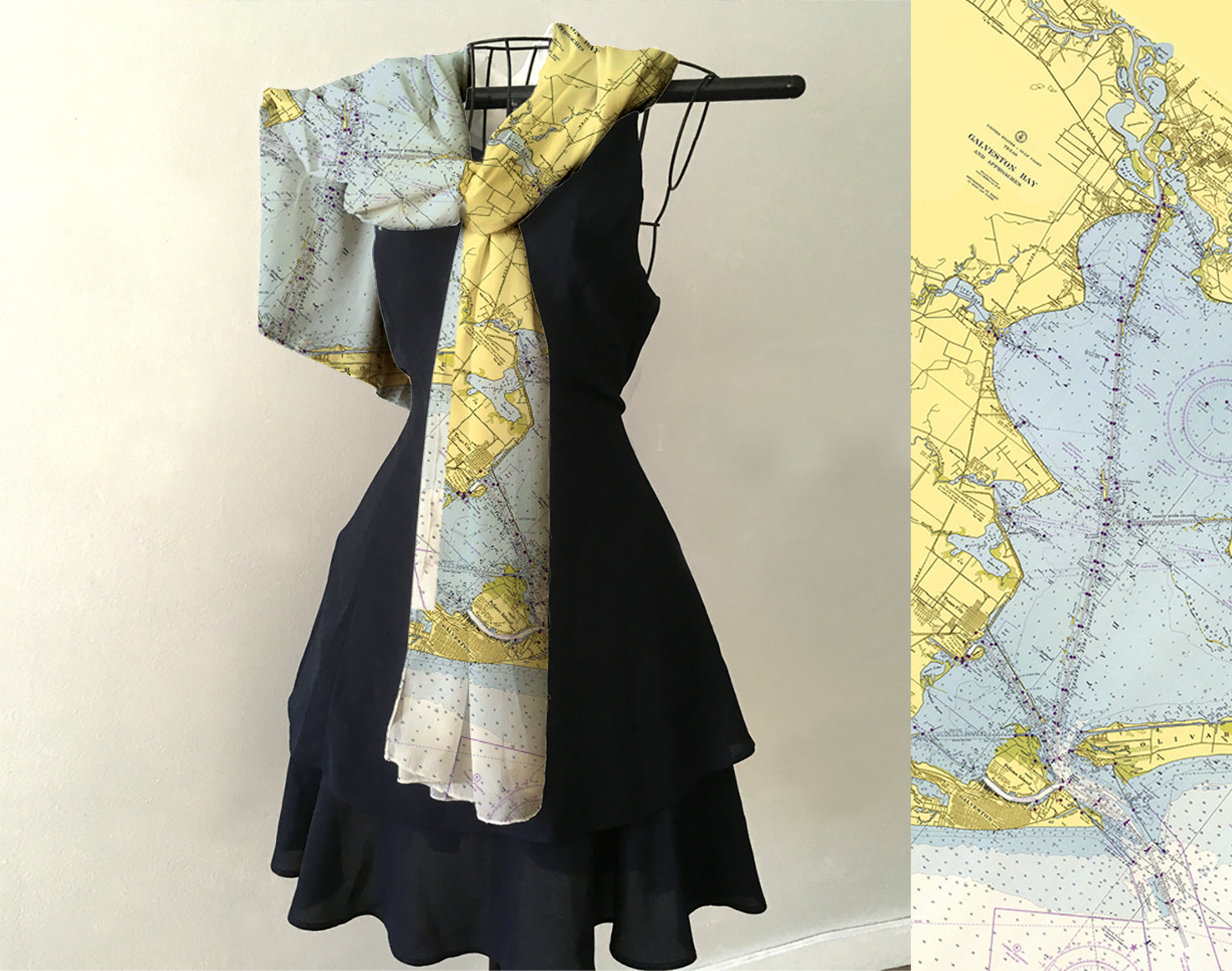 Black dress with a map-patterned scarf on a hanger against a light background