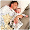 Man and baby lying on a couch together, both wearing matching pajamas.