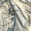 Vintage map with text and topography, partially covered by a textured fabric.