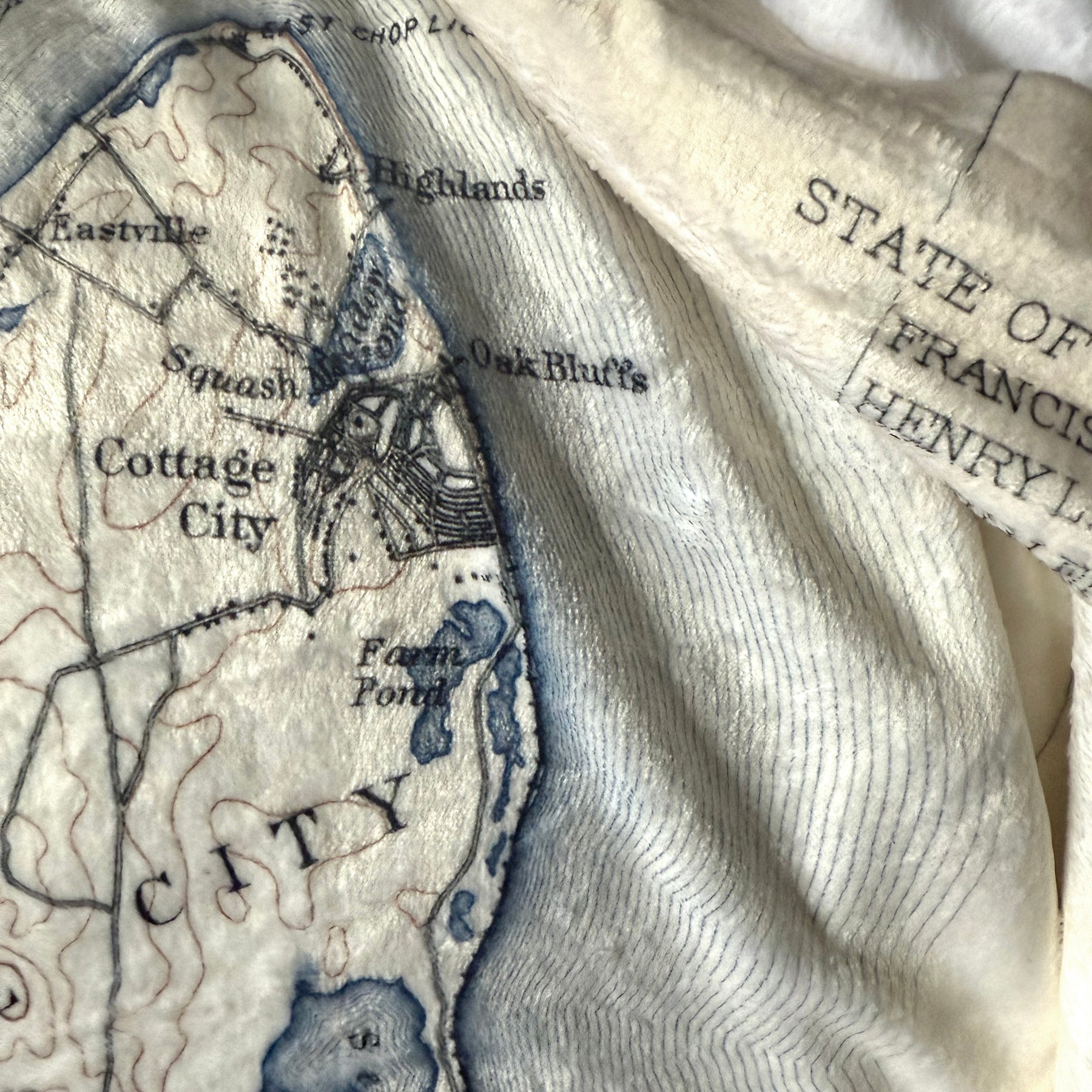 Vintage map with text and topography, partially covered by a textured fabric.